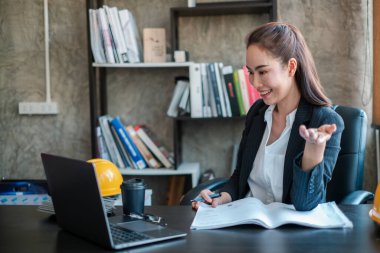 Modern bir ofis ortamında iş kadını, aktif olarak bir video görüşmesine katılıyor, iş gereksinimleri ile çevrili..