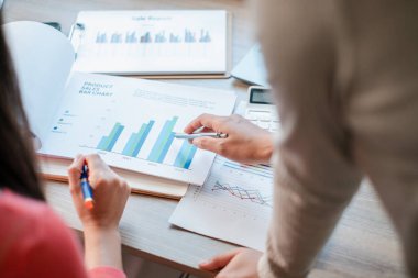 Modern ofis ortamında iş stratejisi ve büyümenin satış grafiklerini ve grafiklerini inceleyen profesyoneller.