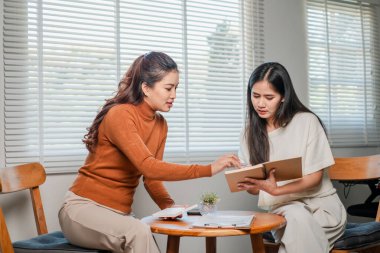 Modern bir ofiste iki kadın, profesyonel bir ortamda takım çalışması ve işbirliğini ön plana çıkarıyor..