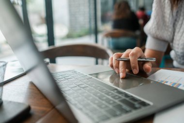 Bilgisayarda çalışan birinin yakın plan fotoğrafı, elinde kalemle verileri analiz ediyor, modern ofis ortamında..