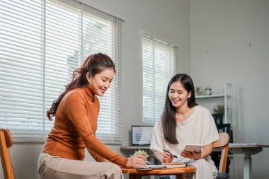İki kadın, doğal ışıklandırmayla aydınlık ve modern bir ofis alanında ortak bir tartışmaya giriştiler..