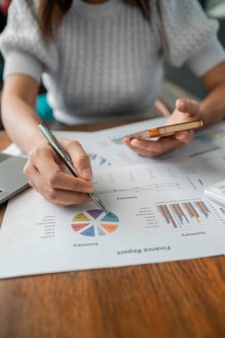 Finansal tabloları ve grafikleri inceleyen, iş analizlerini ve stratejik planlamayı vurgulayan bir kadının yakın çekimi.