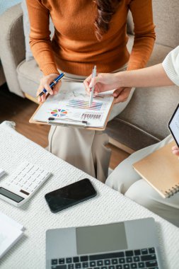 Modern ofis ortamında yapılan bir iş toplantısında finansal tabloları ve verileri inceleyen iki profesyonel..