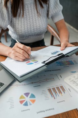 Mali raporları grafik ve grafiklerle inceleyen profesyonel kadın, iş analizi ve stratejisini ön plana çıkarıyor.