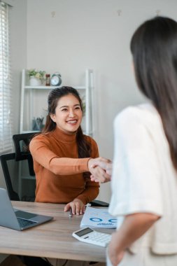 Çağdaş bir ofis ortamında iki kadın iş görüşmesi sırasında profesyonel bir tokalaşmaya giriyorlar..