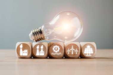 Tahta bloklarda yenilenebilir enerji simgelerine sahip ampul, akıllı şebeke teknolojisini ve sürdürülebilir enerji çözümlerini sembolize ediyor.