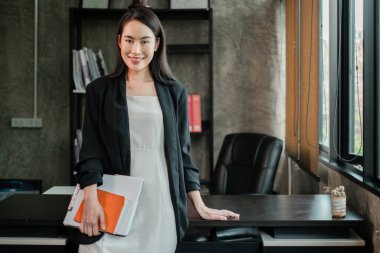 Şık bir ofis ortamında profesyonel bir kadın. Güven ve başarı yayıyor. Belgeler elinde..