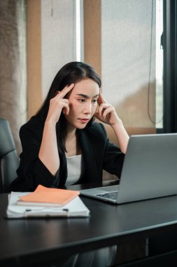 Günümüz ofis ortamında dizüstü bilgisayar üzerinde yoğunlaşan profesyonel kadın, verimlilik ve odaklanma gösteriyor.