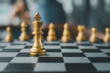 Satranç tahtasındaki altın satranç taşlarının yakın çekimi kralı stratejik bir oyun ayarında vurguluyor..