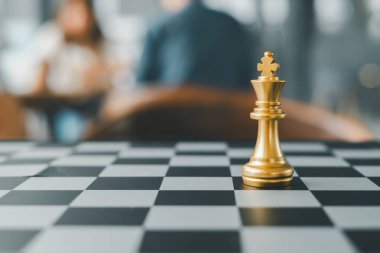 Bulanık bir geçmişi olan, strateji ve liderliği sembolize eden, kareli bir tahtadaki altın satranç kralının yakın çekimi..