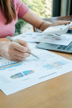 Finansal tabloları inceleyen ve iş analizi ve planlama için hesap makinesi kullanan bir kadının yakın çekimi..