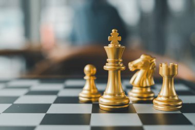 Satranç tahtasındaki altın satranç taşlarının yakın çekimi, modern bir ortamda strateji ve rekabeti vurguluyor.