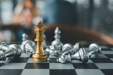 Altın bir satranç kralı zaferi ve stratejiyi simgeleyen gümüş parçalarla çevrili bir satranç tahtasında muzaffer bir şekilde duruyor..