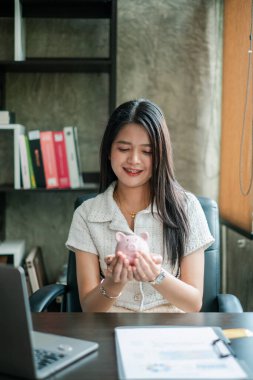 Elinde kumbarası olan genç bir kadın, tasarruf ve finansal planlamayı simgeliyor..