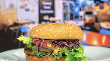 Susamlı çörek, sulu köfte, gevrek marul, dilimlenmiş domates ve dilimlenmiş mor lahana soslu taze yapılmış bir hamburgerin yakın çekimi..