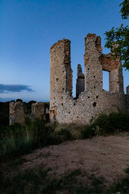 Tarihi bir taş harabe alacakaranlık gökyüzüne karşı dimdik duruyor. Etrafı yeşillik ve gün ışığıyla çevrili..