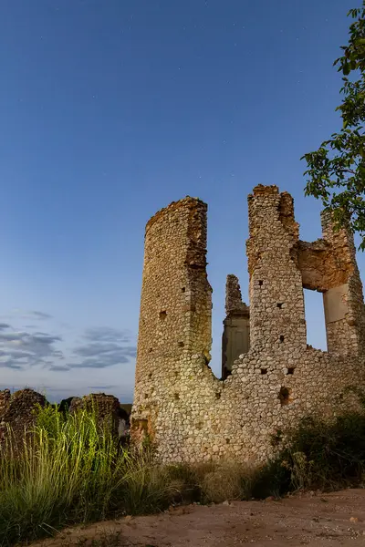 Taştan kalıntılar yıldızlı bir gökyüzünün altında duruyor, geceleri sessiz bir kırsal alanda çimlerle çevrili..