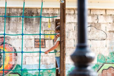 Genç bir çocuk, canlı bir duvar resmine tırmanma çerçevesi ile neşeyle etkileşime girer..
