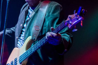 Bir müzisyen ustaca bas gitar çalar, seyirciyi canlı bir performans içinde ritim ve enerjiye bağlar..