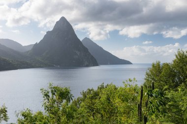 View from near Rachette Point of the St. Lucia Pitons.  Looking south across lush green foliage of Soufriere Bay and the famous Petit Piton and Gros Piton in the distance on the island of Saint Lucia. clipart