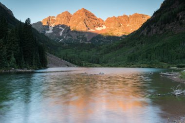 Yazın ortasında Maroon Bells Sunrise. Manzaralı manzaralar için popüler bir yer. Maroon Bells dünyanın her yerinden birçok insan tarafından takdir edilir. Bu sabahın erken saatlerinde Maroon Gölü 'ndeki hareketli sudan yayılmış bir yansıması var.. 