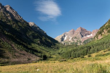 Yüksek Tepeler Maroon Gölü 'nün yukarısında Meşhur Maroon Bells' le birlikte bir fon olarak yükselir. Dünyanın dört bir yanından gelen turistler tarafından ziyaret edilen vadiyi çevreleyen Kestane Çanları Karlı Toprak Bölgesi.