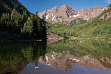 Maroon Bells, Maroon Gölü 'ndeki sabah ışığının dinginliği ile yansıtılır. Dünyanın her yerinden gelen turistler tarafından ziyaret edilir..