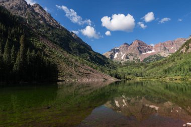 Yüksek Tepeler Maroon Gölü 'nün yukarısında Meşhur Maroon Bells' le birlikte bir fon olarak yükselir. Dünyanın dört bir yanından gelen turistler tarafından ziyaret edilen vadiyi çevreleyen Kestane Çanları Karlı Toprak Bölgesi.