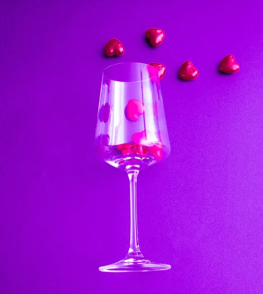 在紫色的背景上 是满满一杯红心的酒杯 — 图库照片