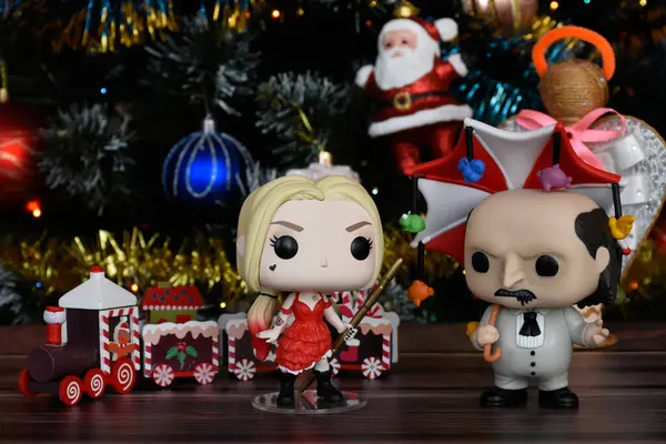 DC çizgi roman kahramanları Harley Quinn ve Penguen 'in aksiyon figürleri. Süslü Noel ağacı, küçük ahşap tren, şenlikli dekor..