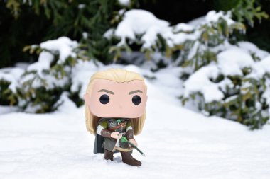 Fantezi filmi Yüzüklerin Efendisi 'ndeki Elf Legolas' ın aksiyon figürü. Ok ve yay tutan savaşçı. Kış ormanı, kar yağışı, yeşil orman.