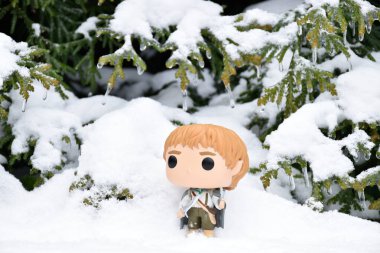 Funko Pop action figure of hobbit Sam with sword and phial's light from fantasy movie The Lord of the Rings. Winter forest, snow drifts, green woods. clipart