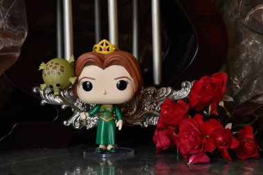 Popüler animasyon filmi Shrek 'ten Prenses Fiona' nın Funko Pop oyuncağı. Sütunları, kırmızı gülleri, kahverengi örtüsü, mermer zemini, yansıması olan muhteşem saray..