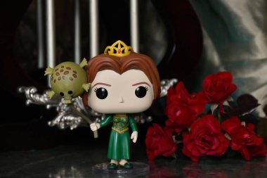 Popüler animasyon filmi Shrek 'ten Prenses Fiona' nın Funko Pop oyuncağı. Sütunları, kırmızı gülleri, kahverengi örtüsü, mermer zemini, yansıması olan muhteşem saray..