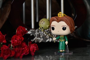 Popüler animasyon filmi Shrek 'ten Prenses Fiona' nın Funko Pop oyuncağı. Sütunları, kırmızı gülleri, kahverengi örtüsü, mermer zemini, yansıması olan muhteşem saray..