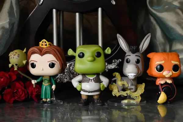 Funko Pop action figures of princess Fiona, ogre Shrek, Donkey and Puss in Boots. Fabulous palace with columns, red roses, green canopy, marble floors.