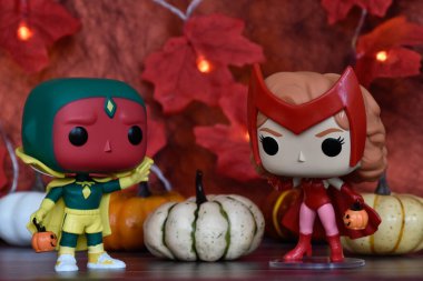 Marvel 'in süper kahramanları Vision ve Cadılar Bayramı kostümlü Kızıl Cadı Wanda' nın aksiyon figürleri. Renkli balkabakları, kırmızı yapraklar, çelenk ışıkları, ürkütücü.