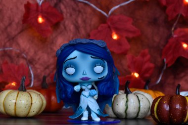 Funko Pop action figure of Emily from dark fantasy gothic animated film Corpse Bride. Halloween decor, pumpkins, red leaves, garland lights, spooky mood. clipart