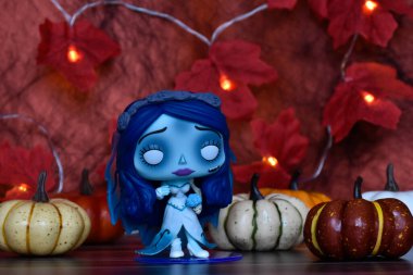 Funko Pop action figure of Emily from dark fantasy gothic animated film Corpse Bride. Halloween decor, pumpkins, red leaves, garland lights, spooky mood. clipart