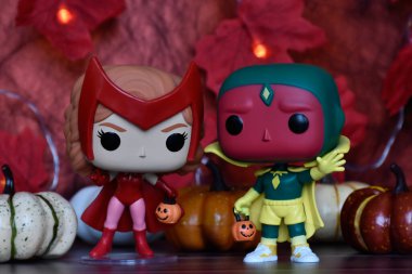 Marvel süper kahramanları Kırmızı Cadı Wanda ve Vizyon 'un Cadılar Bayramı kostümlü Funko Pop aksiyon figürleri. Renkli balkabakları, kırmızı yapraklar, çelenk ışıkları, ürkütücü.