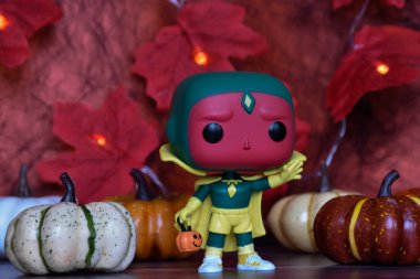 Wanda Vision dizisindeki Cadılar Bayramı kostümü içindeki Marvel süper kahraman Vision 'ın Funko Pop aksiyon figürü. Renkli balkabakları, kırmızı yapraklar, çelenk ışıkları.