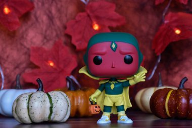 Wanda Vision dizisindeki Cadılar Bayramı kostümü içindeki Marvel süper kahraman Vision 'ın Funko Pop aksiyon figürü. Renkli balkabakları, kırmızı yapraklar, çelenk ışıkları.