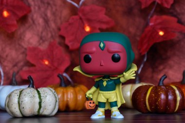 Wanda Vision dizisindeki Cadılar Bayramı kostümü içindeki Marvel süper kahraman Vision 'ın Funko Pop aksiyon figürü. Renkli balkabakları, kırmızı yapraklar, çelenk ışıkları.
