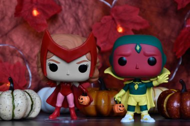 Marvel süper kahramanları Kırmızı Cadı Wanda ve Vizyon 'un Cadılar Bayramı kostümlü Funko Pop aksiyon figürleri. Renkli balkabakları, kırmızı yapraklar, çelenk ışıkları, ürkütücü.