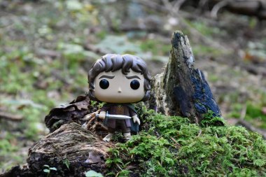 Fantezi filmi Yüzüklerin Efendisi 'ndeki Hobbit Frodo' nun Funko Pop aksiyon figürü. Muhteşem yoğun orman, yeşil yosun, büyük devrilmiş ağaç..