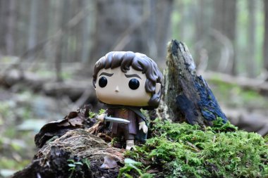 Fantezi filmi Yüzüklerin Efendisi 'ndeki Hobbit Frodo' nun Funko Pop aksiyon figürü. Muhteşem yoğun orman, yeşil yosun, büyük devrilmiş ağaç..