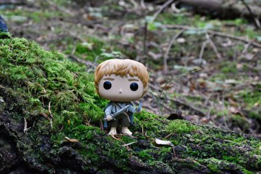 Hobbit Sam 'in fantezi filmi Yüzüklerin Efendisi' ndeki Funko Pop oyuncağı kılıç ve şişe ışığıyla. Muhteşem sık orman, yeşil yosun, devrilmiş ağaç..