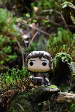 Fantezi filmi Yüzüklerin Efendisi 'ndeki Hobbit Frodo' nun Funko Pop aksiyon figürü. Muhteşem yoğun orman, yeşil yosun, büyük devrilmiş ağaç..