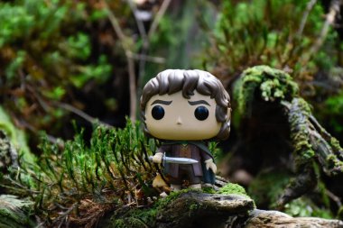Fantezi filmi Yüzüklerin Efendisi 'ndeki Hobbit Frodo' nun Funko Pop aksiyon figürü. Muhteşem yoğun orman, yeşil yosun, büyük devrilmiş ağaç..