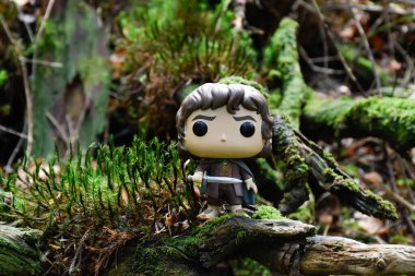 Fantezi filmi Yüzüklerin Efendisi 'ndeki Hobbit Frodo' nun Funko Pop aksiyon figürü. Muhteşem yoğun orman, yeşil yosun, büyük devrilmiş ağaç..